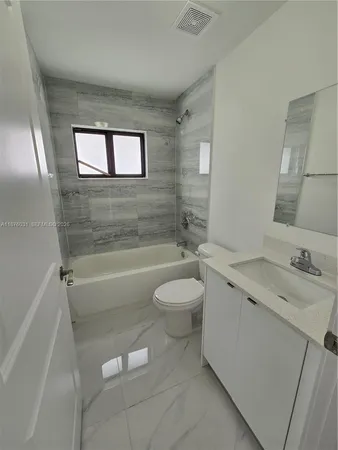 a bathroom with a granite countertop toilet a sink and bathtub