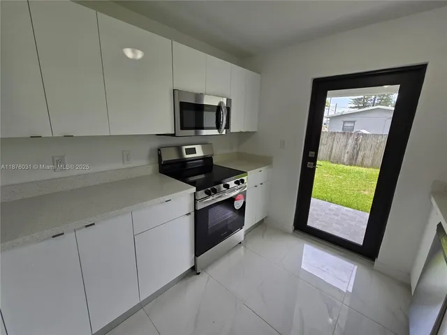 a kitchen with stainless steel appliances granite countertop a stove a sink and a microwave