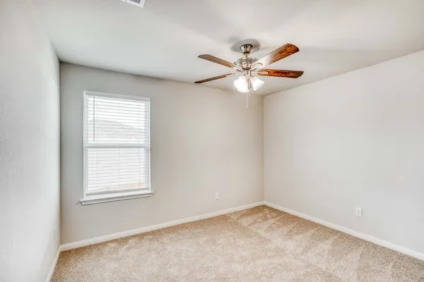 an empty room with a window and a fan