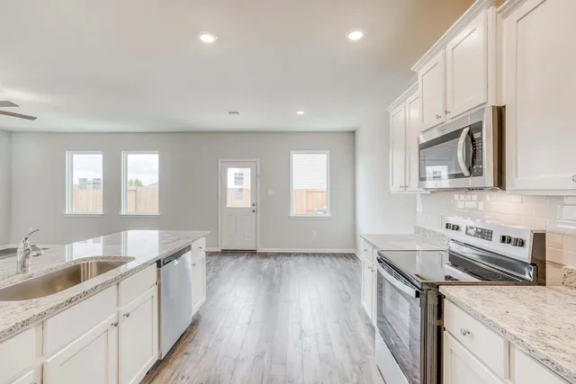 a kitchen with granite countertop a sink wooden floor and stainless steel appliances
