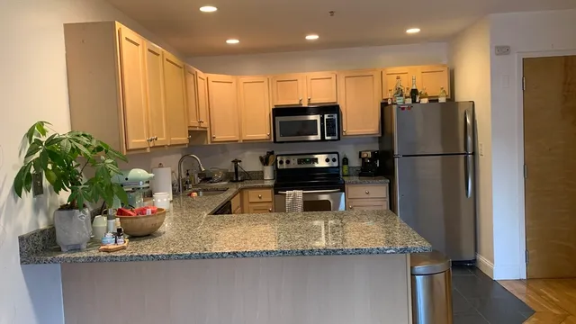 a kitchen with granite countertop a refrigerator a stove a sink a counter space and wooden floor