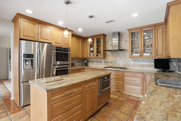 a kitchen with stainless steel appliances granite countertop a refrigerator and a stove top oven