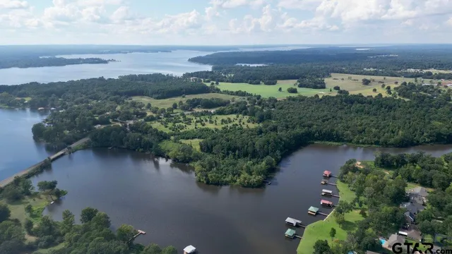 an aerial view of a house with a yard lake and green space