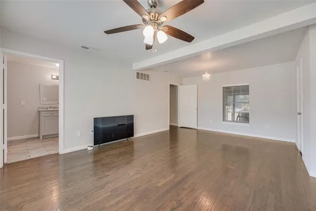 a view of an empty room with window and wooden floor
