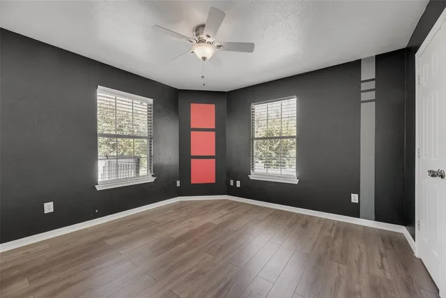 a view of an empty room with a window and wooden floor