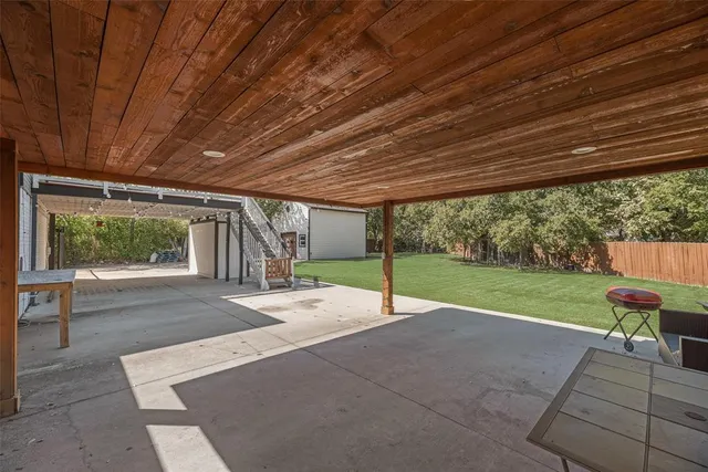 a view of a backyard with table and chairs under an umbrella with a small yard