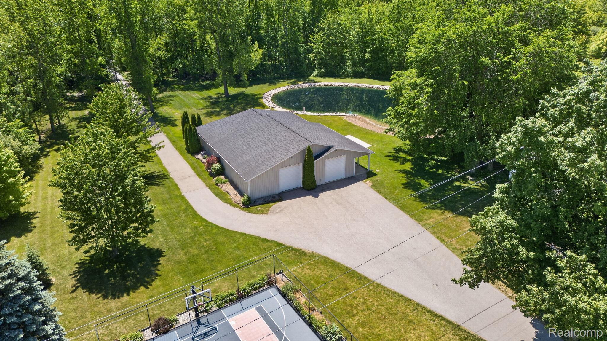 9353 Hill Road Swartz Creek, MI 48473 - Photo 72 of 98 Expansive property featuring a detached outbuilding with two garage doors, a private pond, and a sport court