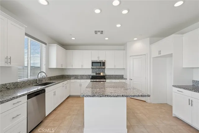 a large kitchen with granite countertop a sink and white cabinets