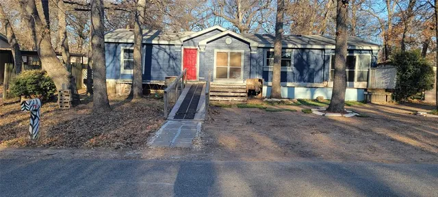 a view of a house with yard and trees in the background