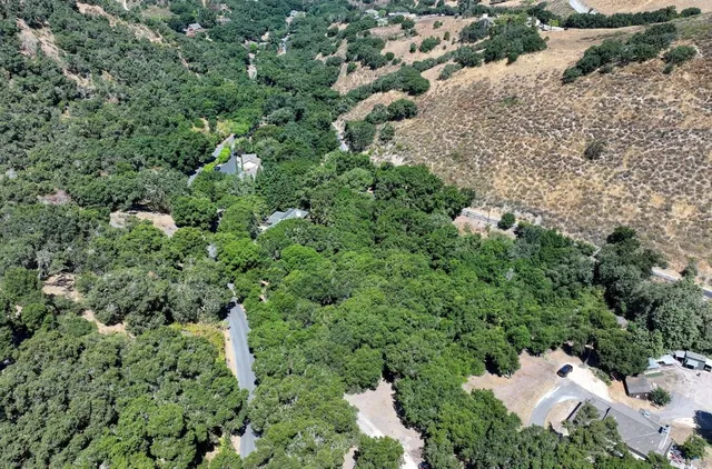 an aerial view of residential house with outdoor space and trees all around