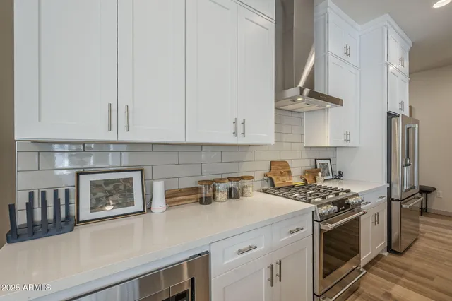a kitchen with stainless steel appliances white cabinets and a stove top oven