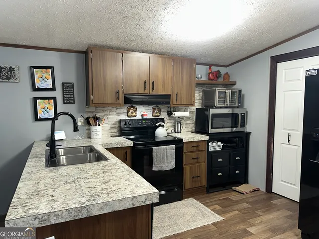 a kitchen with kitchen island granite countertop a refrigerator stove and sink