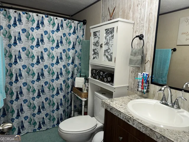 a bathroom with a granite countertop toilet sink and mirror