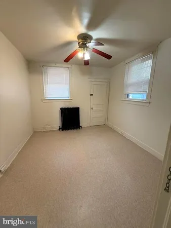 a view of an empty room with a ceiling fan and window