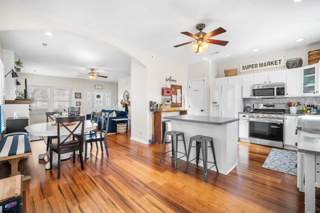 a kitchen with stainless steel appliances granite countertop a stove top oven a refrigerator a dining table and chairs with wooden floor