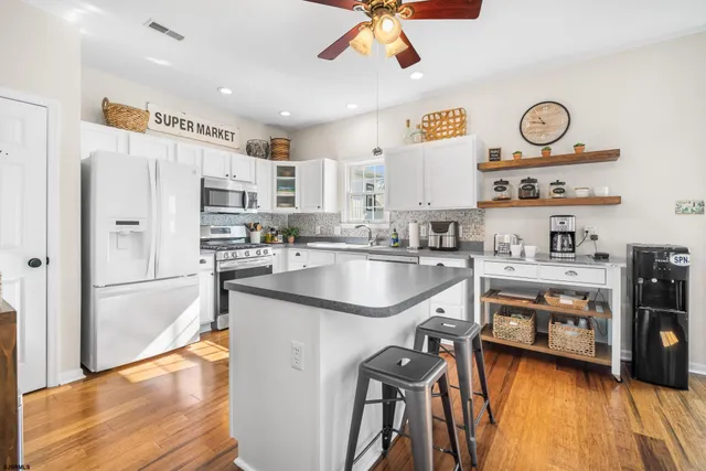 a kitchen with granite countertop a refrigerator a stove a sink and a stove with wooden floor