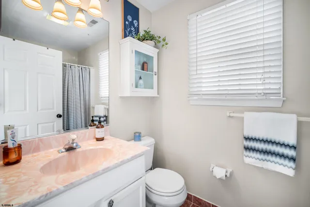 a bathroom with a granite countertop sink a toilet a mirror and shower