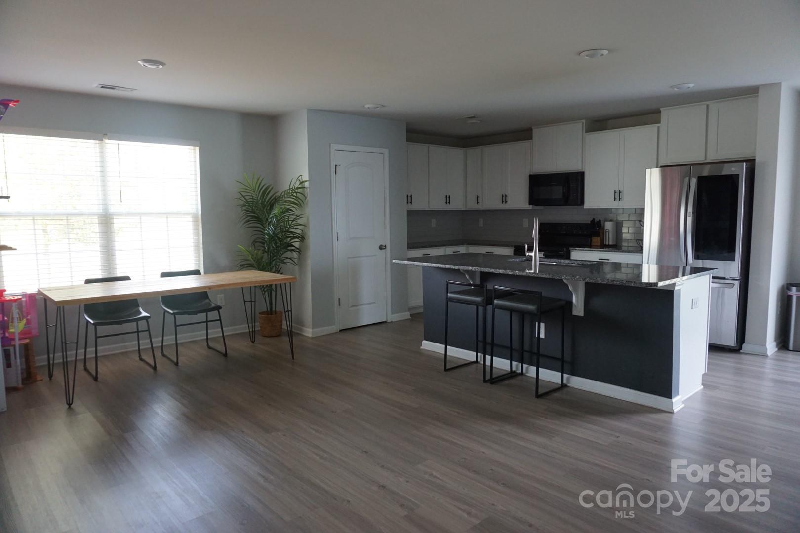 1276 Bryson Lane Denver, NC 28037 - Photo 4 of 16 a kitchen with stainless steel appliances granite countertop a stove top oven a sink a dining table and chairs with wooden floor