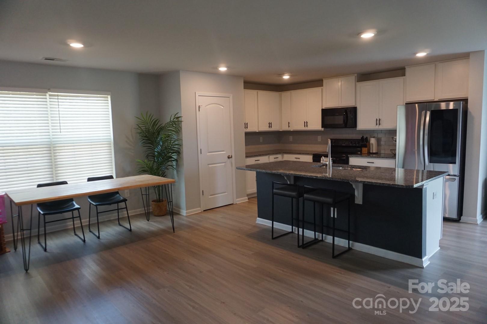 1276 Bryson Lane Denver, NC 28037 - Photo 6 of 16 a kitchen with stainless steel appliances granite countertop a stove a refrigerator a sink a dining table and chairs with wooden floor