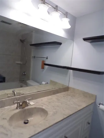 a view of a room with a hanging light and hardwood floor