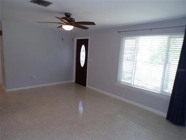 an empty room with a window and a fan