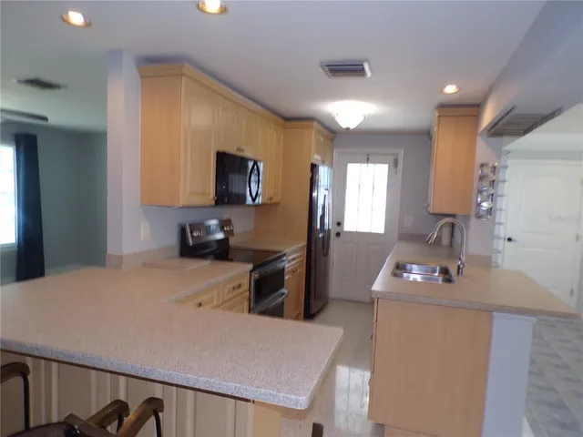 a kitchen with a refrigerator a stove a sink dishwasher a oven with white cabinets and wooden floor