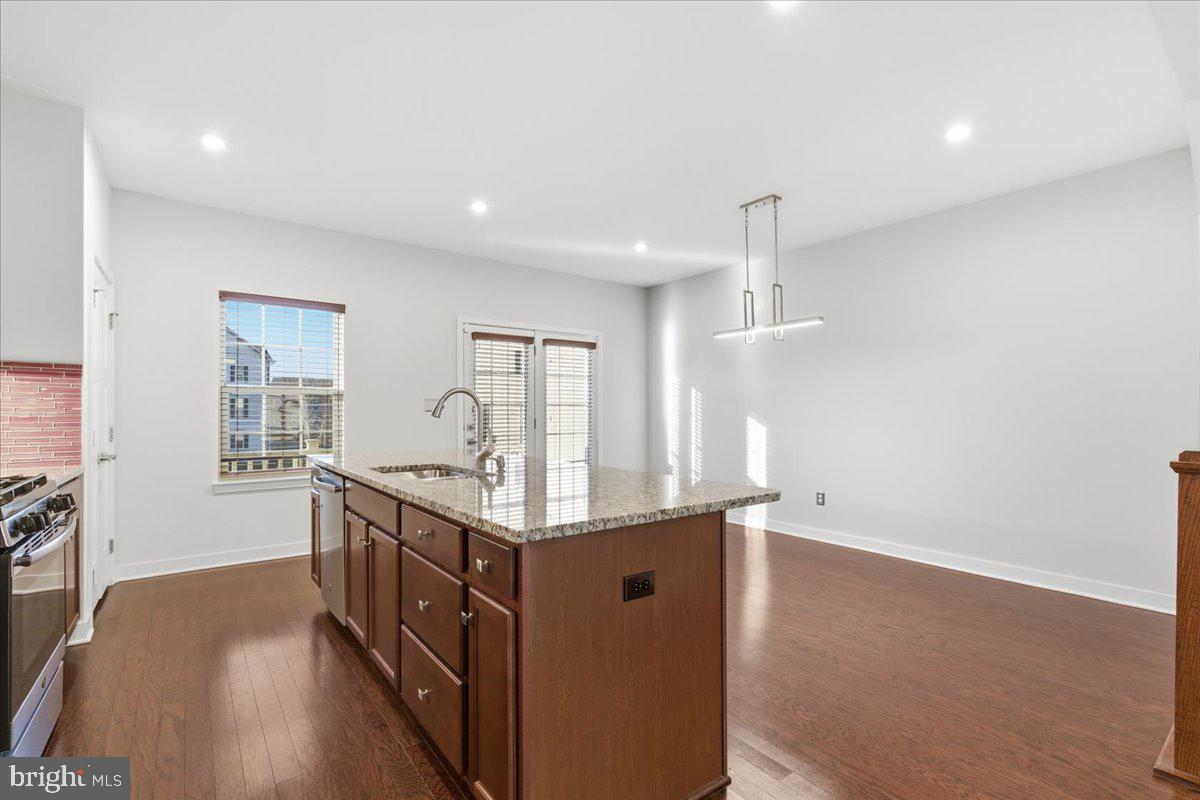 18060 Red Cedar Road Dumfries, VA 22026 - Photo 13 of 39 a kitchen with stainless steel appliances granite countertop a stove a sink and a refrigerator with wooden floor