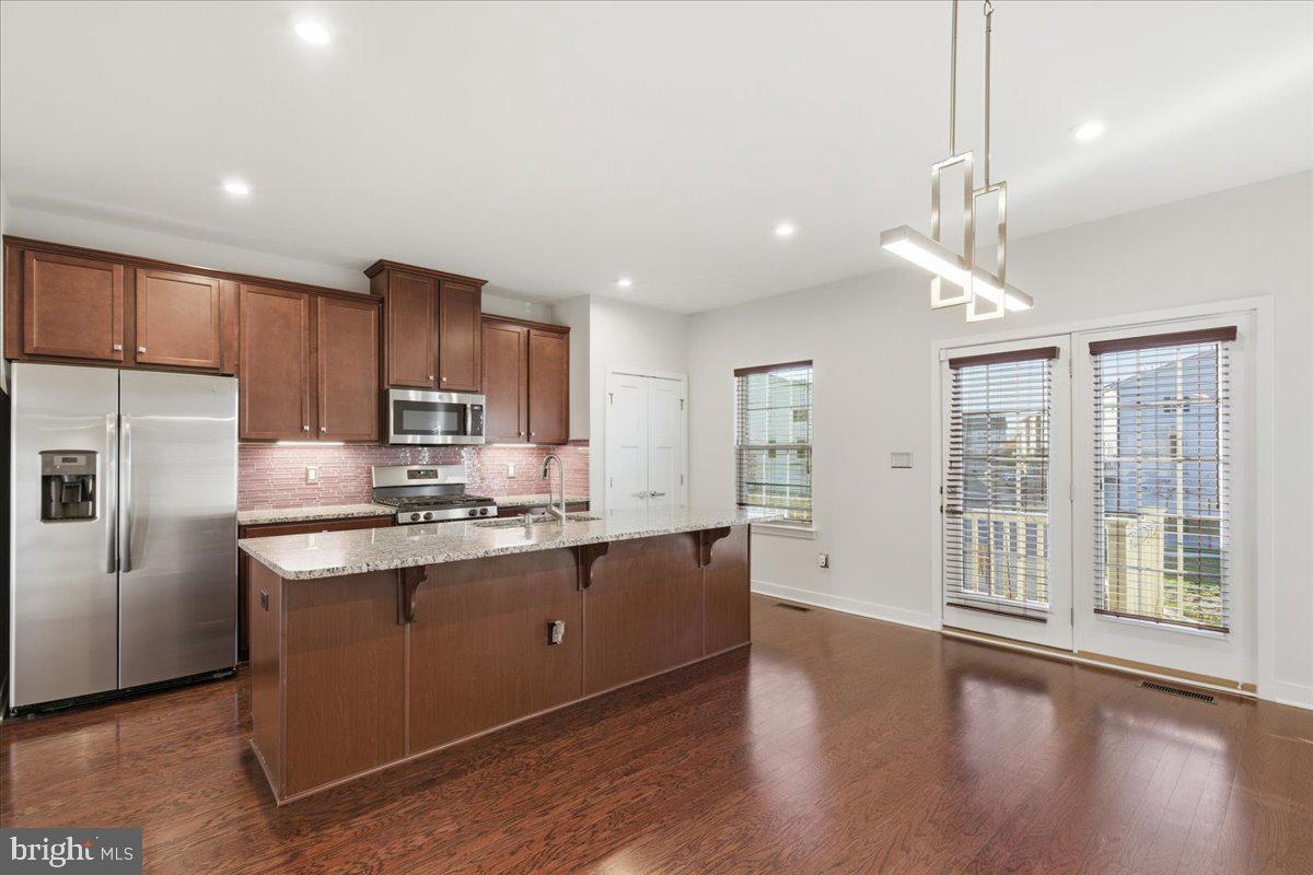 18060 Red Cedar Road Dumfries, VA 22026 - Photo 7 of 39 a kitchen with stainless steel appliances granite countertop a sink a stove a refrigerator cabinets and wooden floor