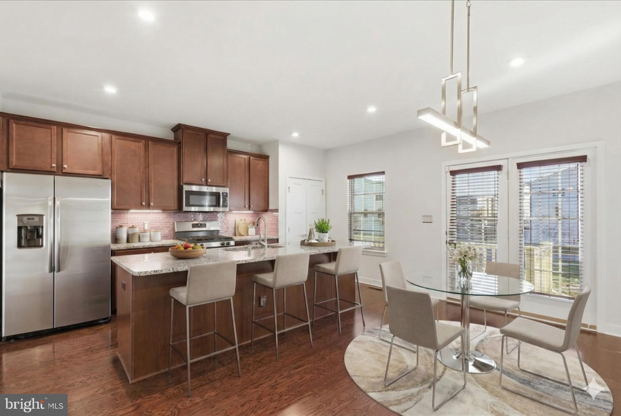 18060 Red Cedar Road Dumfries, VA 22026 - Photo 8 of 39 a kitchen with stainless steel appliances granite countertop a stove a refrigerator a kitchen island a table and chairs