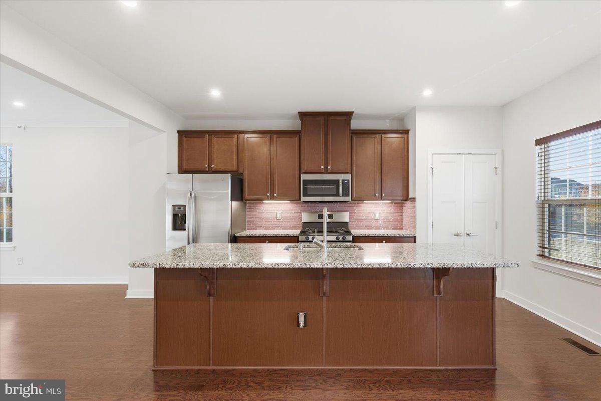 18060 Red Cedar Road Dumfries, VA 22026 - Photo 9 of 39 a kitchen with kitchen island granite countertop a sink window and cabinets