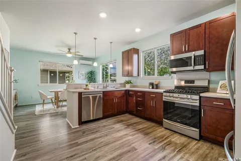 a kitchen with stainless steel appliances granite countertop a stove a sink dishwasher a microwave oven and a dining table with wooden floor