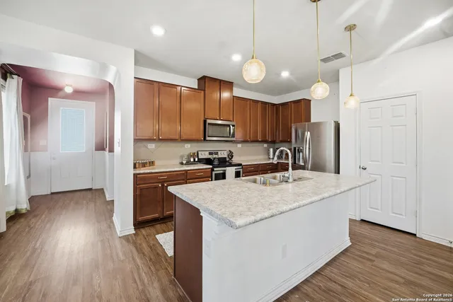 a kitchen with a sink a center island cabinets and a wooden floor