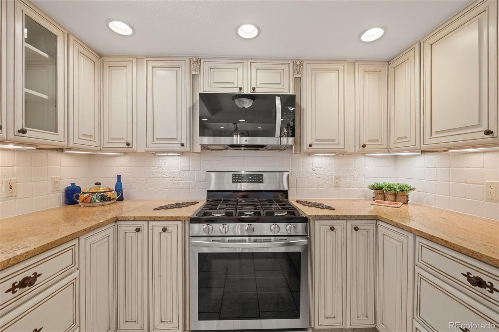 9368 Harvard Drive Highlands Ranch, CO 80130 - Photo 15 of 46 a kitchen with stainless steel appliances granite countertop a stove a sink and a white cabinets