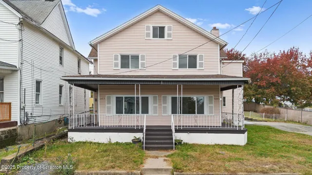 a view of a white house with large windows and a small yard