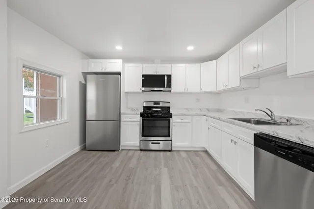 a kitchen with stainless steel appliances granite countertop a stove a sink and white cabinets