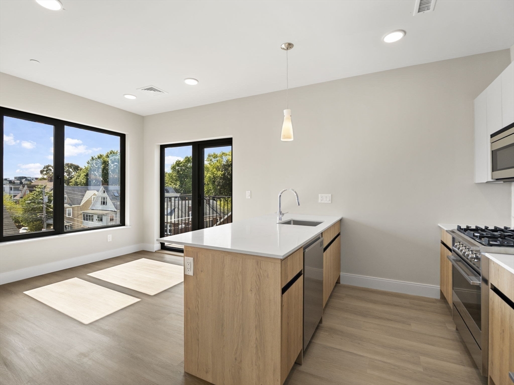 a kitchen with stainless steel appliances granite countertop a sink and a large window