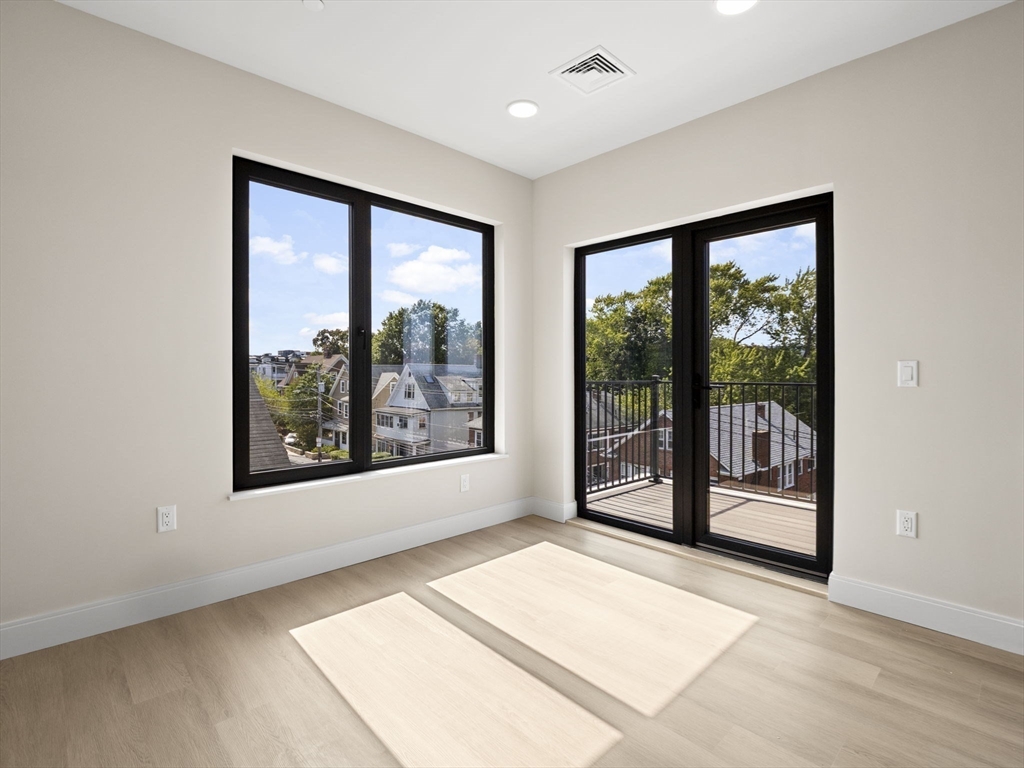 249 Corey Road, Unit 401 Boston, MA 02135 - Photo 13 of 34 an empty room with wooden floor and windows