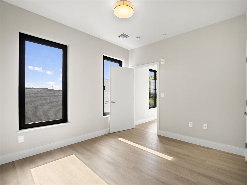 249 Corey Road, Unit 401 Boston, MA 02135 - Photo 18 of 34 an empty room with wooden floor and windows