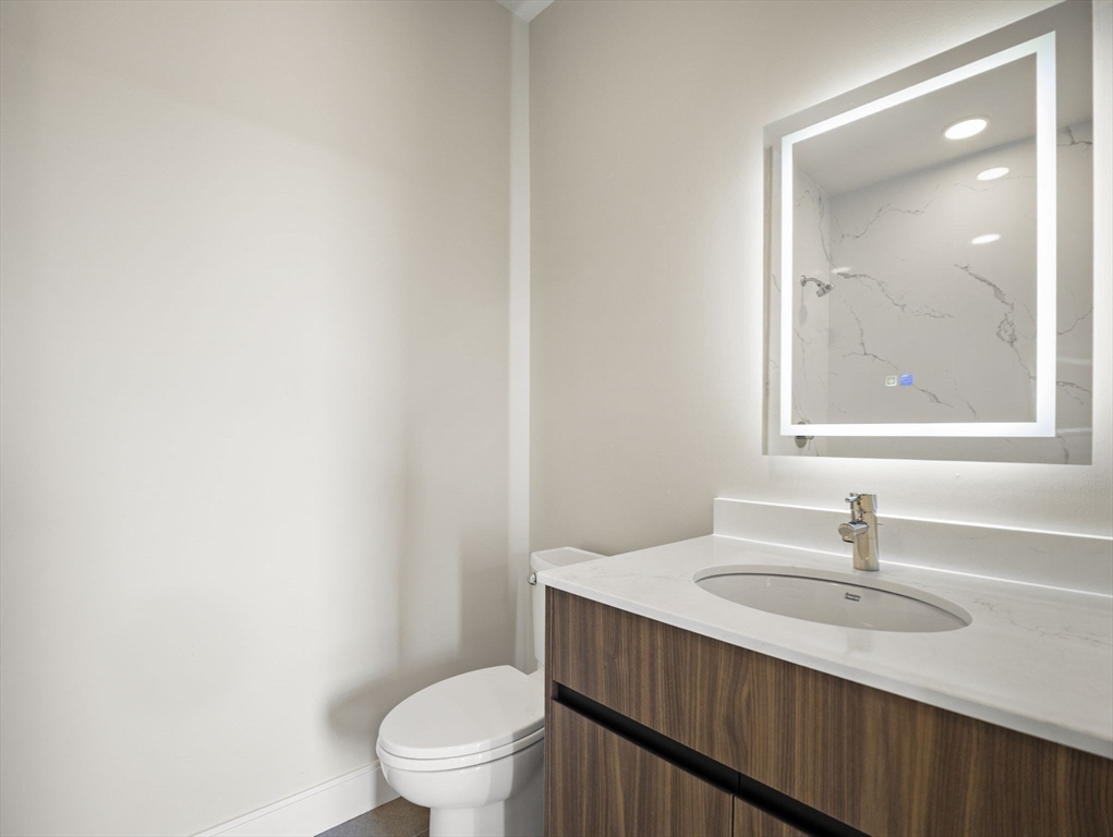 249 Corey Road, Unit 401 Boston, MA 02135 - Photo 19 of 34 a bathroom with a sink a toilet and a mirror