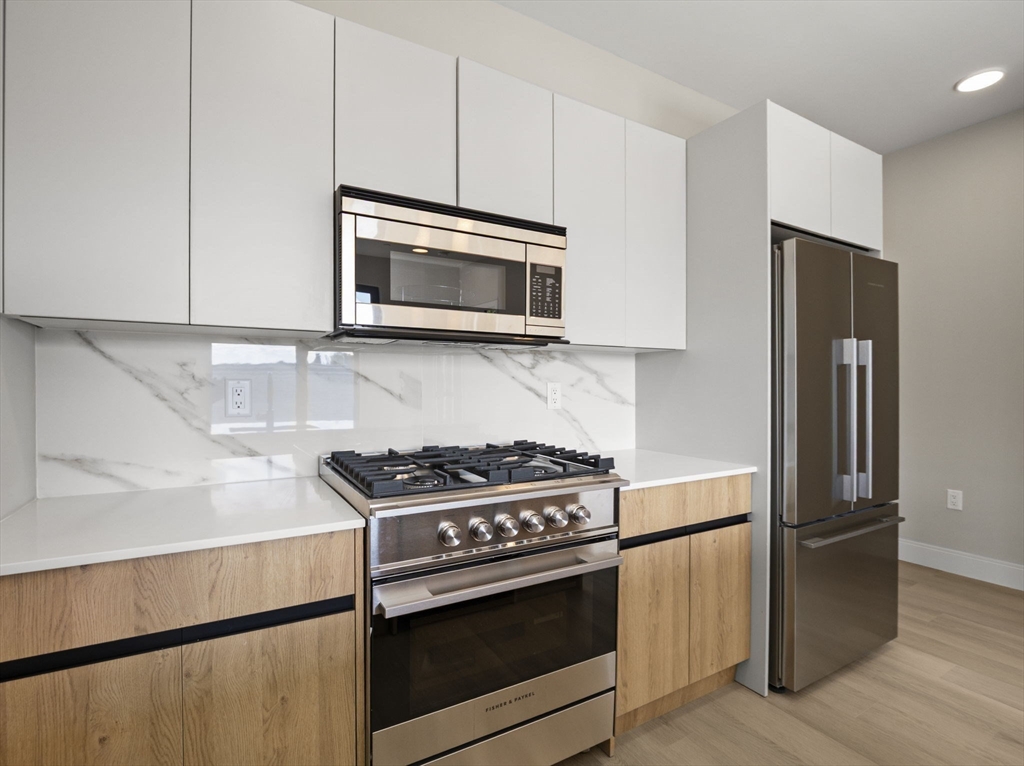 249 Corey Road, Unit 401 Boston, MA 02135 - Photo 5 of 34 a kitchen with stainless steel appliances granite countertop a stove microwave and refrigerator