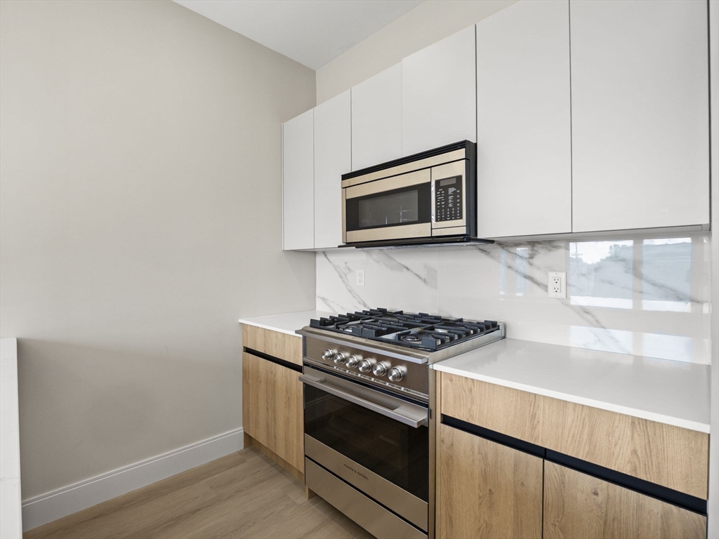 249 Corey Road, Unit 401 Boston, MA 02135 - Photo 6 of 34 a kitchen with granite countertop cabinets stainless steel appliances and wooden floor