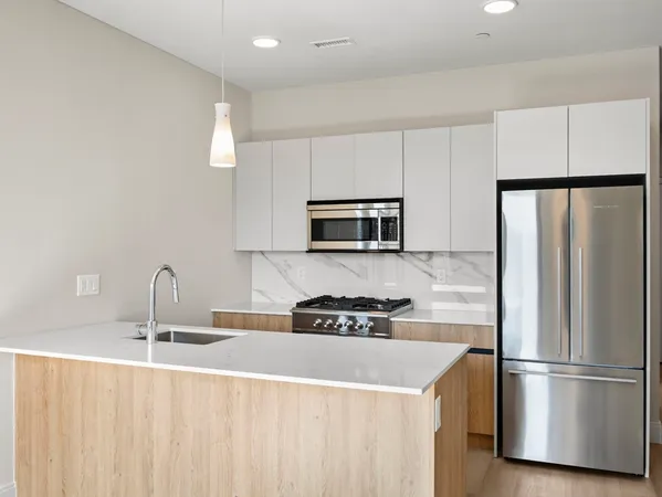 a kitchen with stainless steel appliances granite countertop a refrigerator a sink and white cabinets