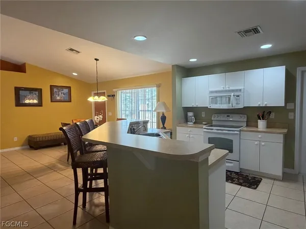a kitchen with a dining table chairs and white cabinets