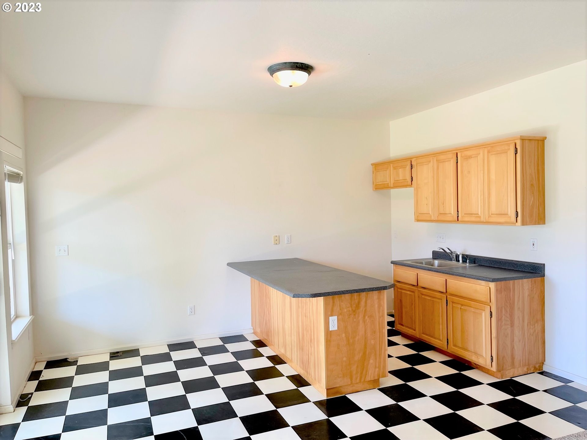 919 3rd Street Brookings, OR 97415 - Photo 31 of 36 a kitchen with a checkered floor and white cabinets