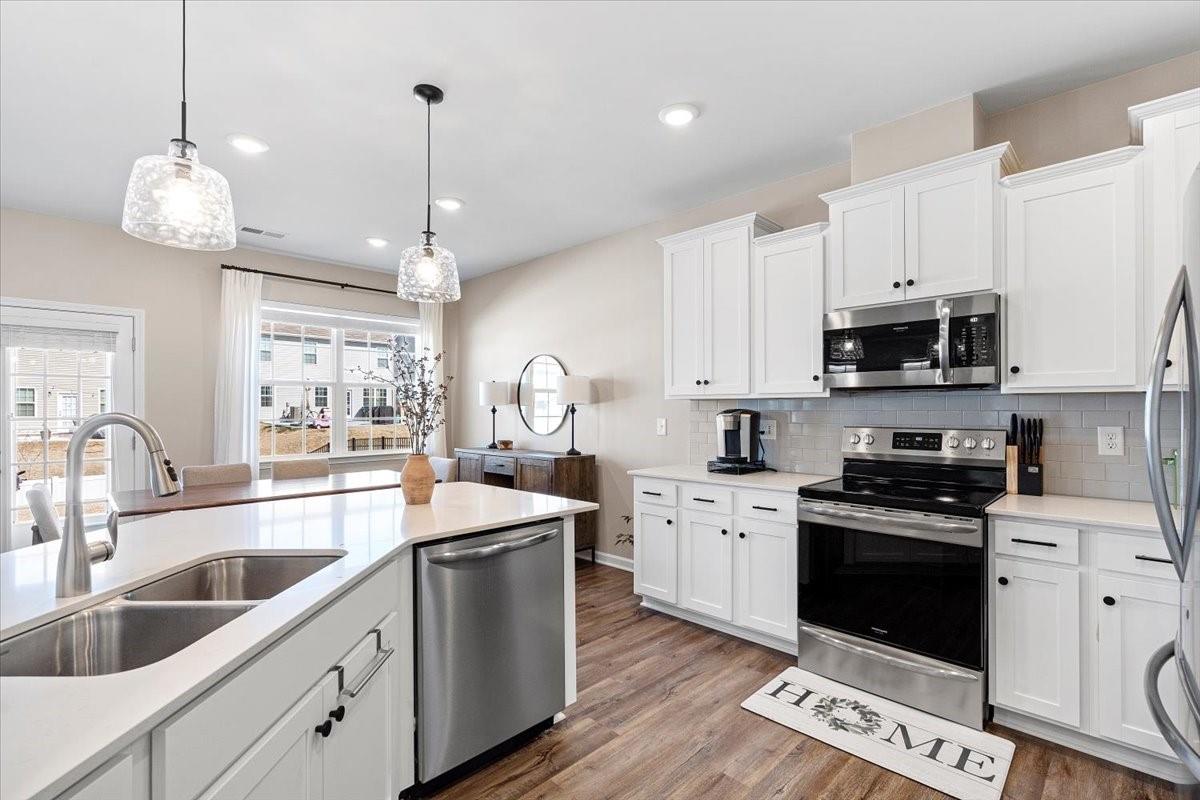 7730 Sea Turtle Way Lancaster, SC 29720 - Photo 6 of 24 a kitchen with stainless steel appliances granite countertop a sink a stove a refrigerator cabinets and a wooden floor