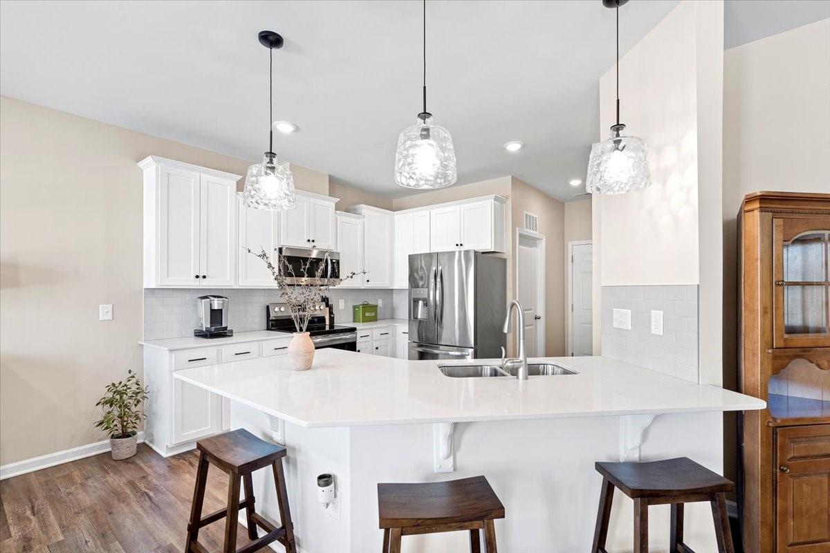 7730 Sea Turtle Way Lancaster, SC 29720 - Photo 7 of 24 a kitchen with stainless steel appliances a dining table chairs and white cabinets