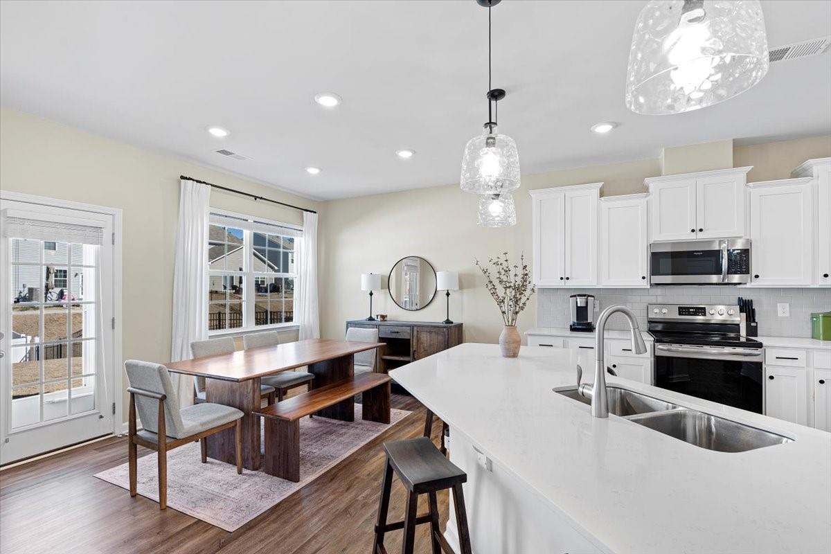 7730 Sea Turtle Way Lancaster, SC 29720 - Photo 8 of 24 a kitchen with a table chairs a sink dishwasher stove and wooden floor