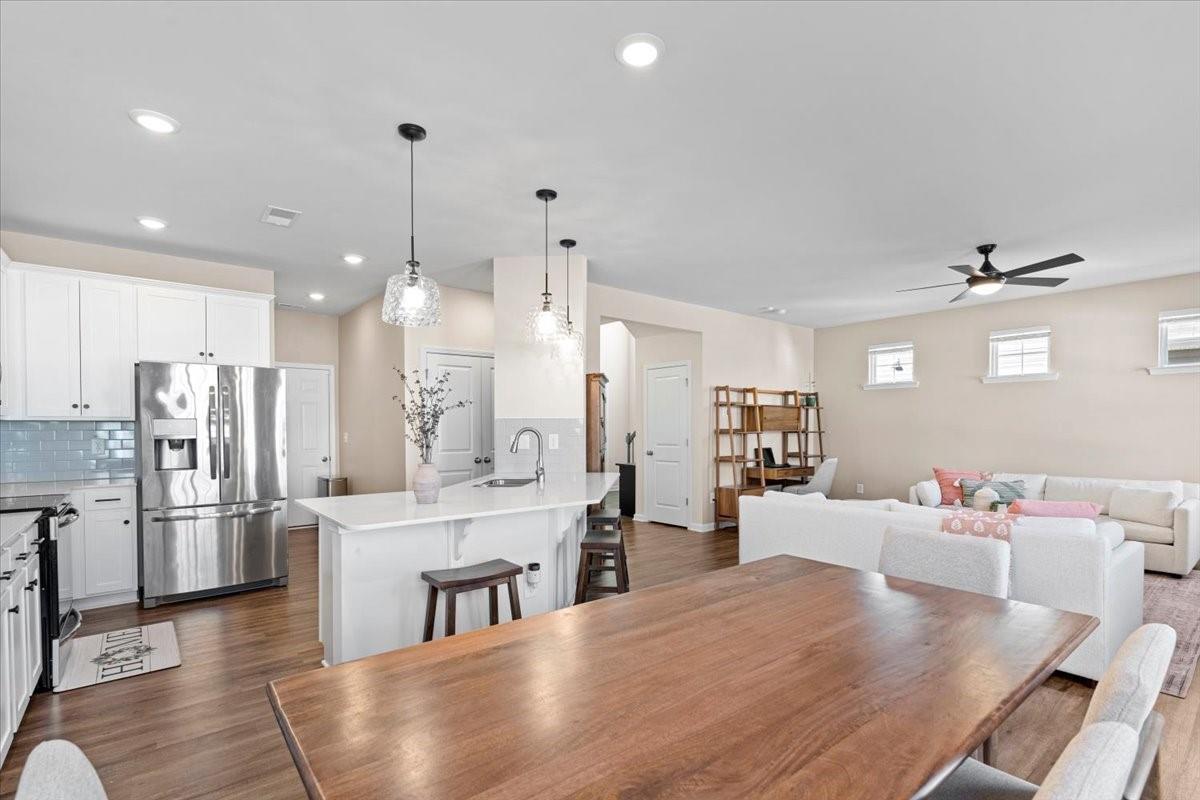 7730 Sea Turtle Way Lancaster, SC 29720 - Photo 10 of 24 a large kitchen with kitchen island a refrigerator a stove a sink a dining table and chairs with wooden floor