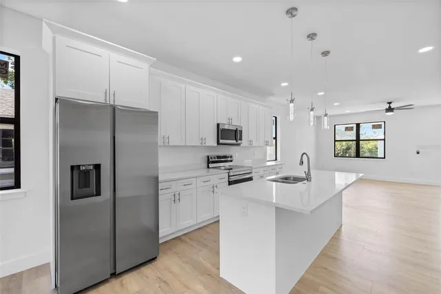 a kitchen with stainless steel appliances kitchen island a refrigerator sink and cabinets