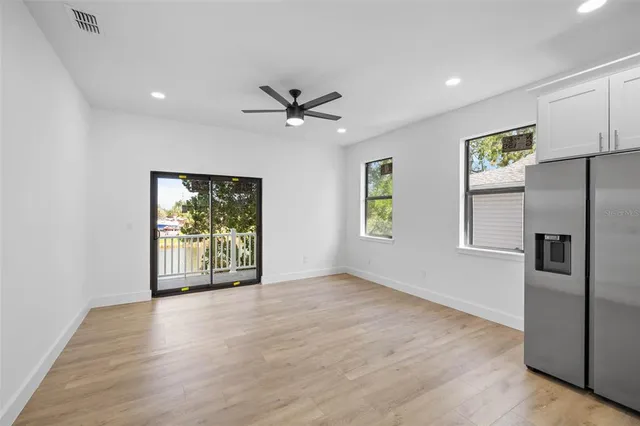 a view of an empty room with a window and kitchen view